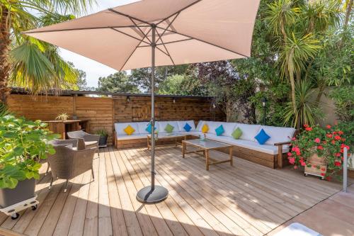a patio with an umbrella and a couch and chairs at La Villa de l'Olivier in Cap d'Agde