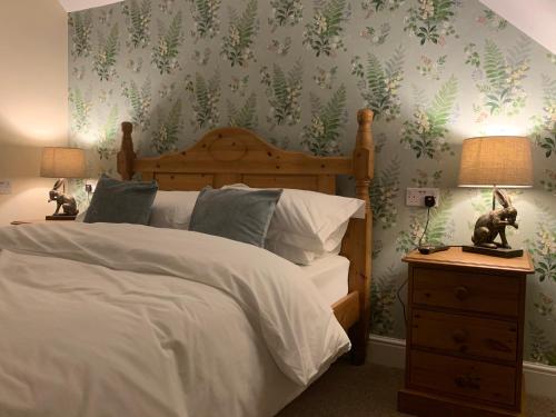 a bedroom with a bed with green leaves on the wall at Lancasters Cottage in Horsham