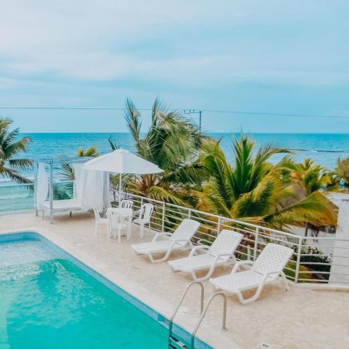 a pool with chairs and an umbrella and the ocean at Green Coveñas by Bernalo Hotels in Coveñas