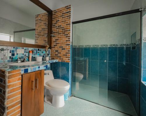 uma casa de banho com um WC, um lavatório e um chuveiro em Oasis Hostel Medellin em Medellín