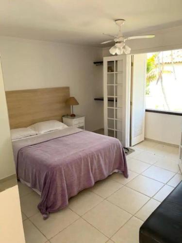 a bedroom with a bed with a purple bedspread on it at Casa com 3 suítes - À 150m da praia de Geribá in Búzios