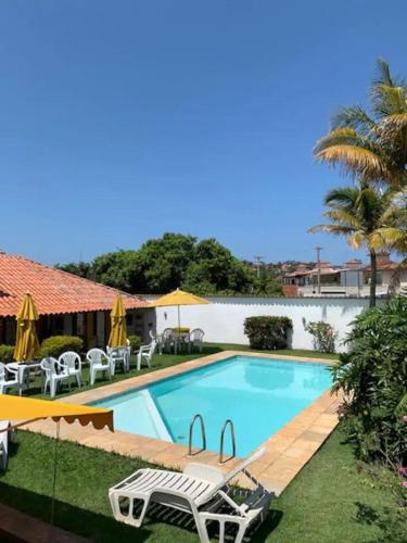 a swimming pool with chairs and umbrellas at Casa com 3 suítes - À 150m da praia de Geribá in Búzios