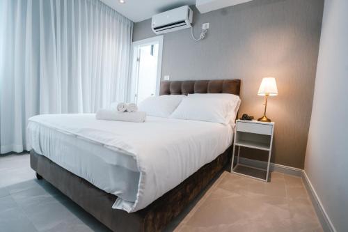 - une chambre avec un grand lit blanc et une fenêtre dans l'établissement Unique Hotel Ashdod, à Ashdod