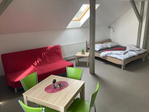 Cette chambre comprend un canapé rouge, une table et des chaises. dans l'établissement Apartmány V ráji, à Žďár