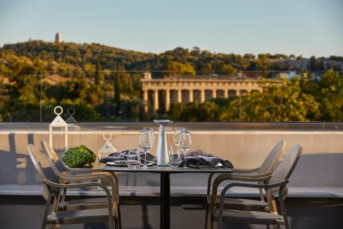 a table with chairs and wine glasses on a balcony at MiraMe Athens Boutique Hotel in Athens