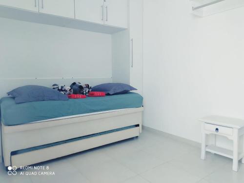 a bedroom with a bed with blue sheets and a table at Casa-2 Condomínio Elza em Arraial do Cabo in Arraial do Cabo