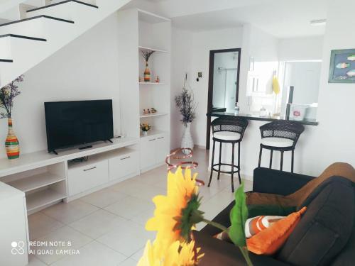 a living room with a tv and a couch and chairs at Casa-2 Condomínio Elza em Arraial do Cabo in Arraial do Cabo