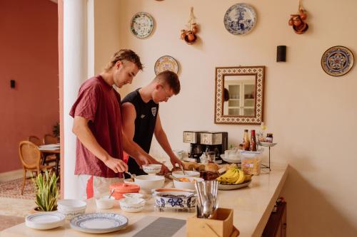 dos personas de pie en una cocina preparando comida en Hotel & Hostal Boutique Casa Garza, en Mérida
