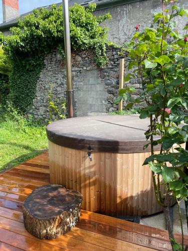 a wooden hot tub with a tree stump sitting on a deck at Le petit Monrepos avec jacuzzi nordique in Bielle
