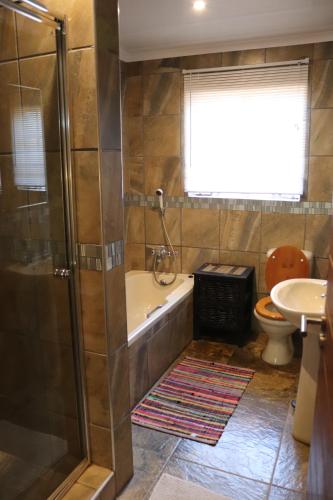 Un baño con bañera, inodoro y lavabo. en Mellivora Lodge, en Marloth Park