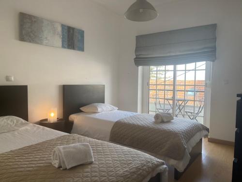 een hotelkamer met 2 bedden en een raam bij TEJO HOUSE RIVER Lisbon (Cacilhas) in Almada