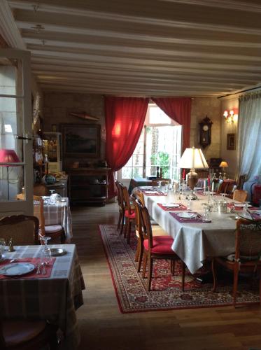 a dining room with tables and chairs with red curtains at Au Relais Saint Maurice in Chinon