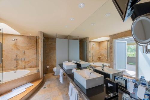 ein Badezimmer mit zwei Waschbecken, einer Badewanne und einem Spiegel in der Unterkunft Hotel Intercontinental Medellín, an IHG Hotel in Medellín