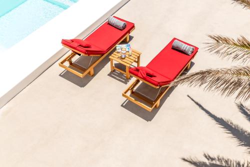 two red chairs and a table on the beach at O Lofos Luxury Boutique Suites in Agios Stefanos