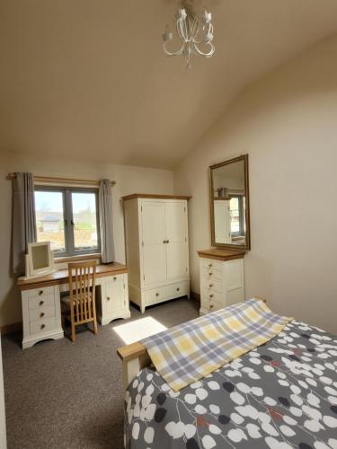 a bedroom with a bed and a desk and a mirror at Swallow cottage, Over Kellet in Over Kellet