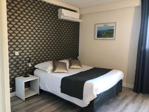 a bedroom with a bed and a wall at Hotel Alpes Cevennes in Guilherand
