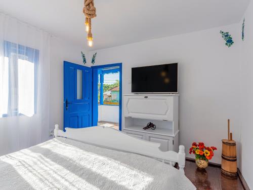 - une chambre blanche avec un lit et une porte bleue dans l'établissement Casa de vacanta traditionala romaneasca, à Schiuleşti
