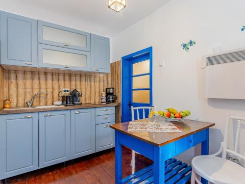 a kitchen with blue cabinets and a bowl of fruit on a table at Casa de vacanta traditionala romaneasca in Schiuleşti