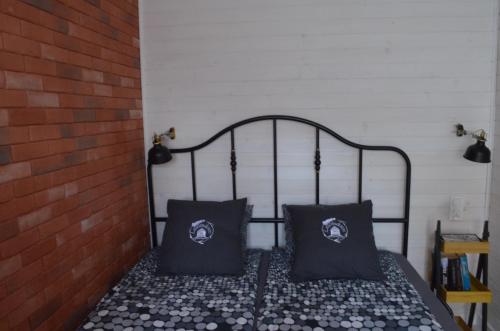 a bed with two black pillows sitting next to a brick wall at Lawendowo- sauna, basen, domki w ogrodzie i apartamenty w kamienicy in Sandomierz