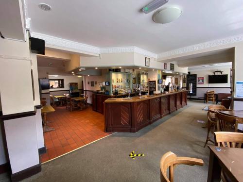 a large room with a bar and some tables and chairs at The Plough Inn Wigston in Wigston Magna