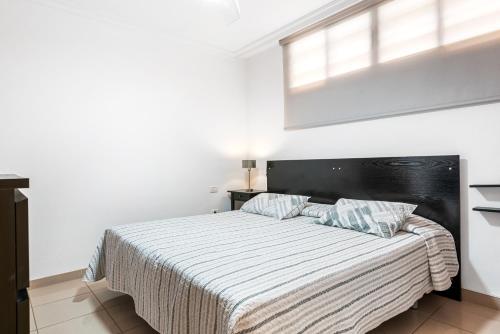 sypialnia z łóżkiem z czarnym zagłówkiem i oknem w obiekcie Apartamento Los Seres 212 w mieście Los Cristianos