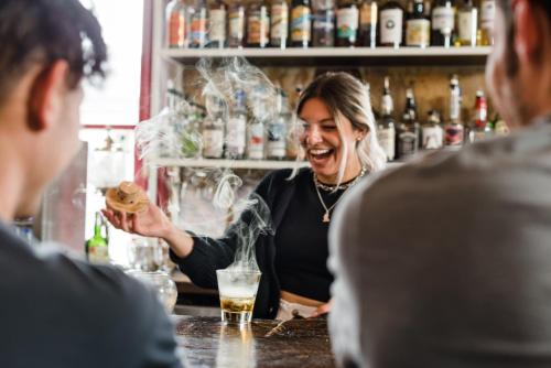 a woman standing behind a bar holding a sandwich at Hostel Fish in Denver