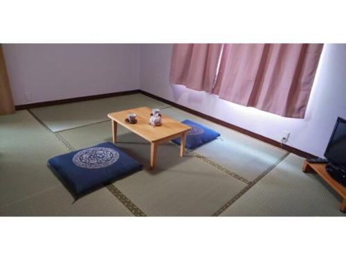 a room with a table and two ottomans at Guest House Fukuchan - Vacation STAY 34479v in Kaiyo