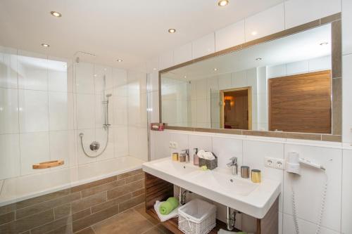 La salle de bains est pourvue d'un lavabo, d'une baignoire et d'un miroir. dans l'établissement Ferienwohnung "Mein Alpenjuwel", à Filzmoos