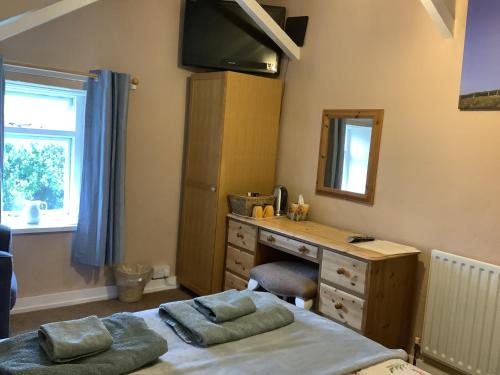 a bedroom with a desk and a dresser with two pillows at Haelarcher Farmhouse and Helicopter B&B in Lizard
