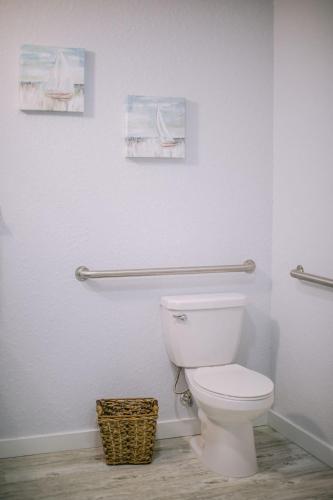 a bathroom with a toilet with two pictures on the wall at Vistalmar Beach Resort in Deerfield Beach