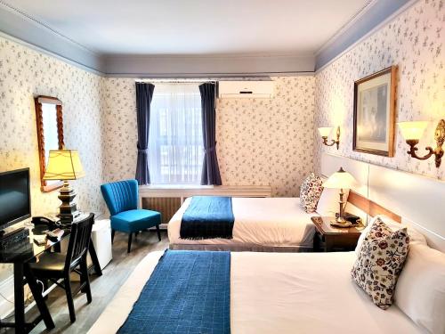 a hotel room with two beds and a desk at Le Chateau de Pierre in Quebec City