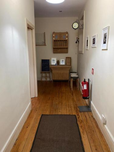 a living room with a wooden floor and a clock on the wall at Hostel Brazuca in Porto