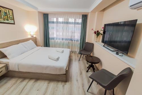 ein Hotelzimmer mit einem Bett, einem Schreibtisch und einem TV in der Unterkunft Hotel Pushkin II/1a in Kutaissi