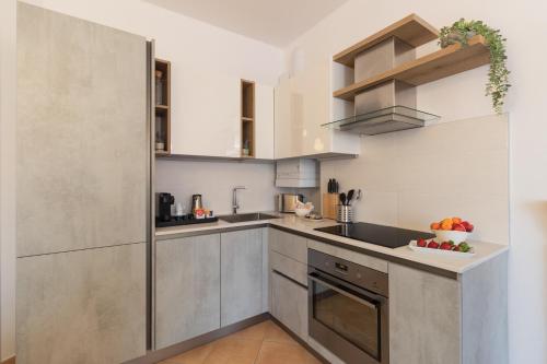 a kitchen with white walls and a stainless steel refrigerator at Casa del Borgo "Terra & Fuoco" sul Lago Maggiore in Maccagno Inferiore