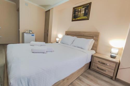 ein Schlafzimmer mit einem großen weißen Bett und einem Nachttisch in der Unterkunft Hotel Pushkin II/1a in Kutaissi