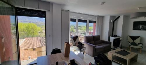 a living room with a couch and a large window at Apartamentos Miradores del Isasa in Herce