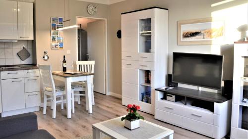 Il comprend une cuisine et un salon avec une table et une télévision. dans l'établissement Südwäldchen, à Westerland