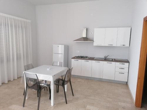 a white kitchen with a white table and chairs at Zibibbo Beach Apartments - Trapani in Trapani
