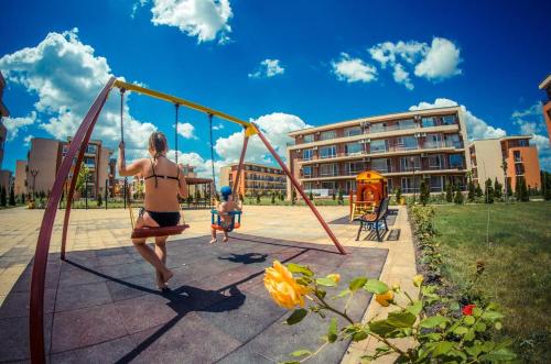 uma mulher e uma criança a brincar num baloiço em HOLIDAY ORCHID FORT GARDEN - Premium Apartments em Sunny Beach