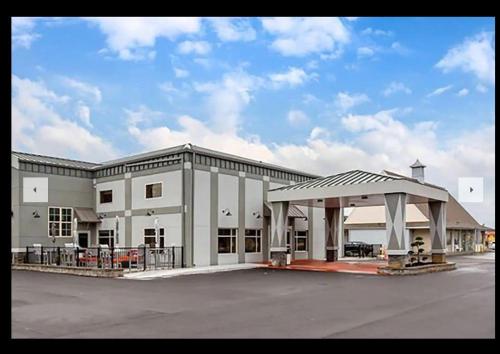 a large building with a pavilion in a parking lot at Days Inn & Suites by Wyndham Bowling Green in Bowling Green