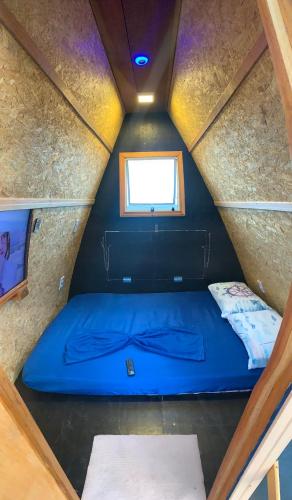 a blue bed in a small room with a window at Chalé Jorai - pé na areia in Bertioga