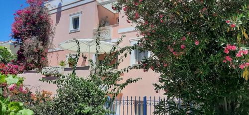 a pink building with flowers and an umbrella at Villa Rodanthos in Perdika