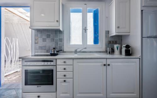 a white kitchen with a sink and a stove at Aphrodite by Akroploro in Pollonia