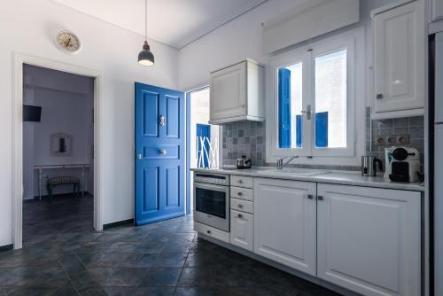 a kitchen with white cabinets and a blue door at Aphrodite by Akroploro in Pollonia