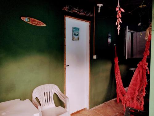 a green room with a white door and a chair at Pertinho prahia toninhas in Ubatuba