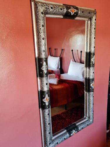 a mirror hanging on a wall with a bed at Chez Laila in Skoura
