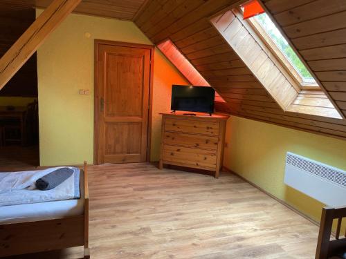 a attic room with a bed and a tv and a window at EDER- Penzion & Apartmány in Horní Planá