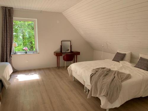 a white bedroom with two beds and a window at Villa Baldringe in Ystad