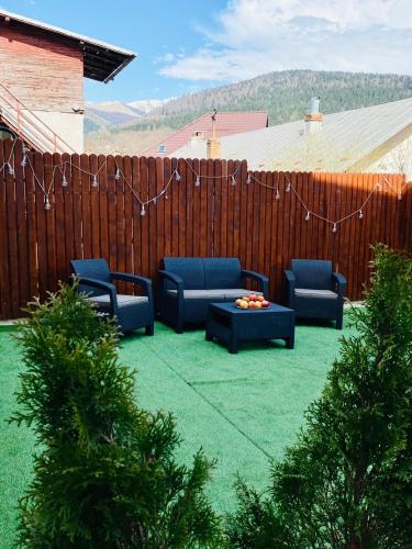 a patio with blue chairs and a table and a fence at CASA ANKELI in Buşteni