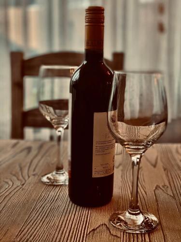 a bottle of wine and two wine glasses on a table at CASA ANKELI in Buşteni